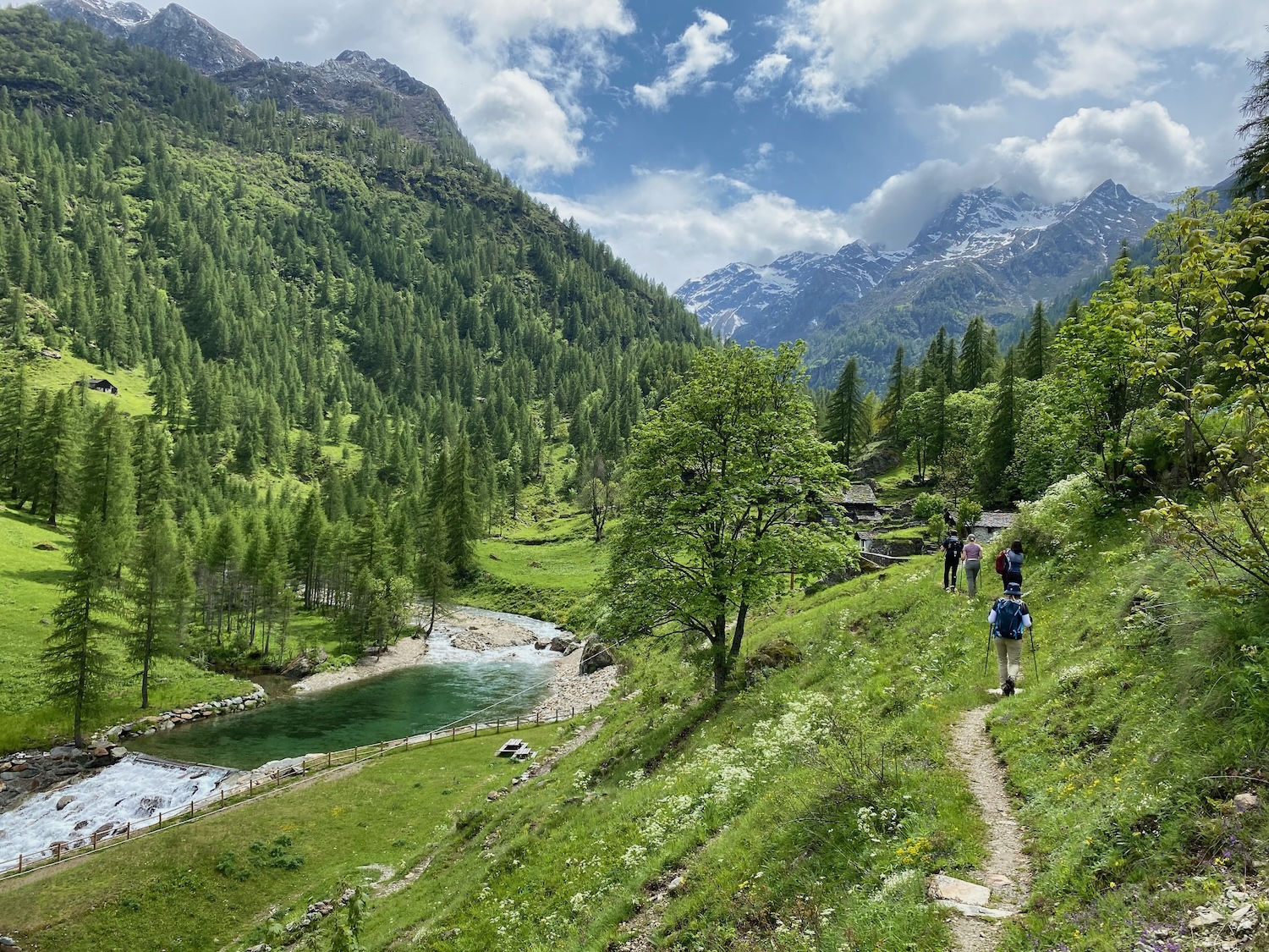 hikers in valley beside river Italian Alps