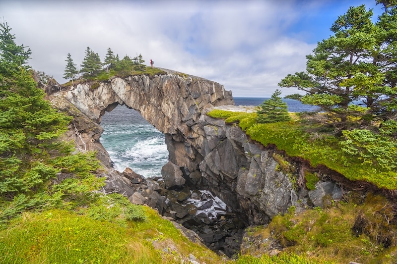 hiker crosses natural rock formation on east coast trail in newfoundland canada