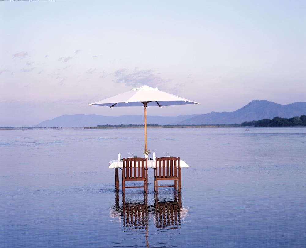 dinner table in water with mountain view zambia